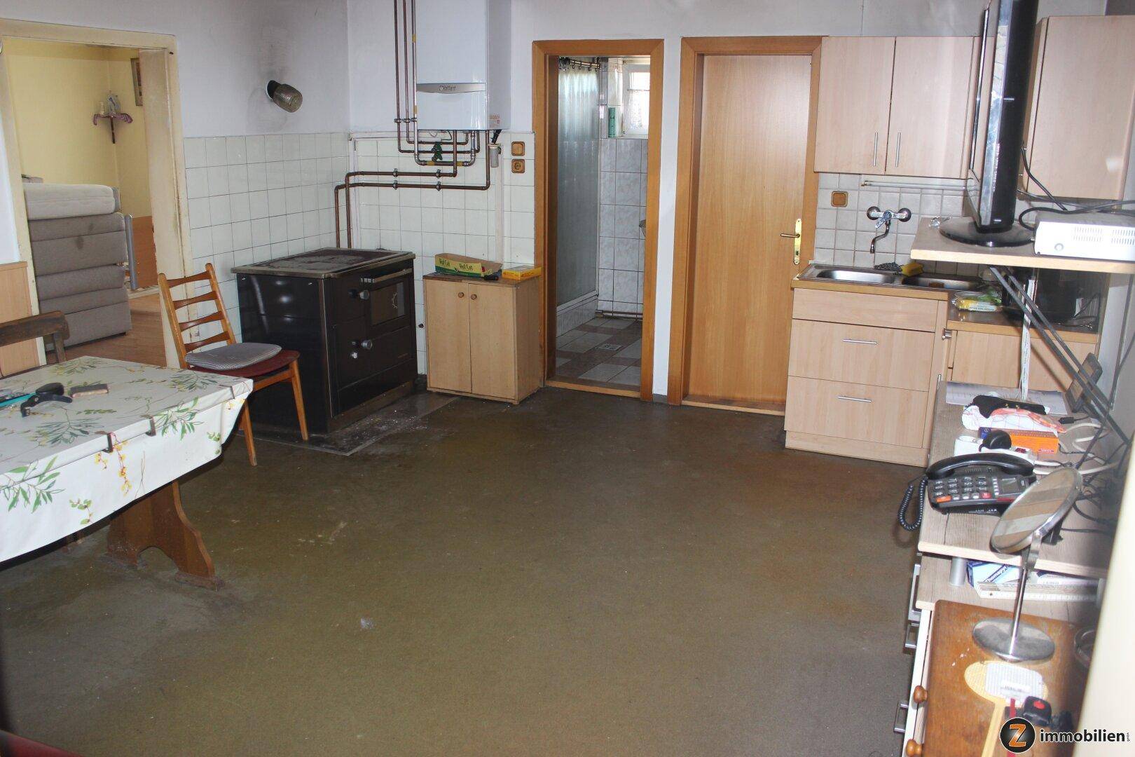 Rustikale Küche mit traditionellem Holzofen, Spüle und einfachen Holzschränken.