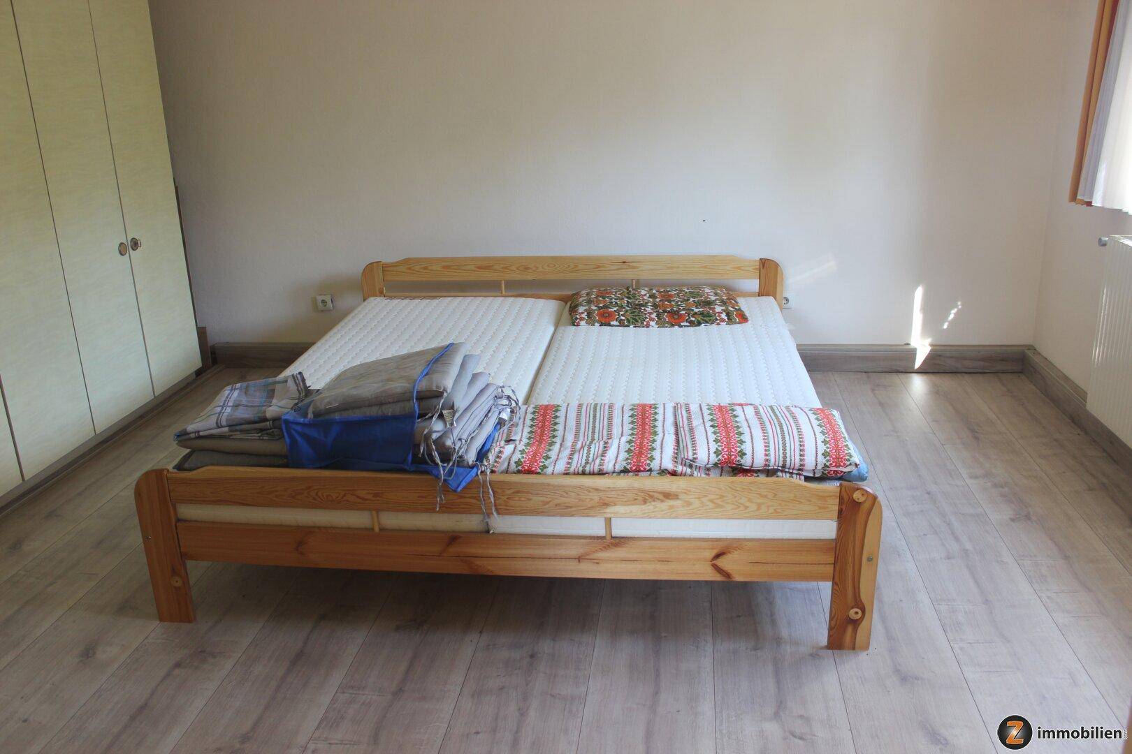 Schlafzimmer mit Doppelbett, Laminatboden und Einbauschrank.