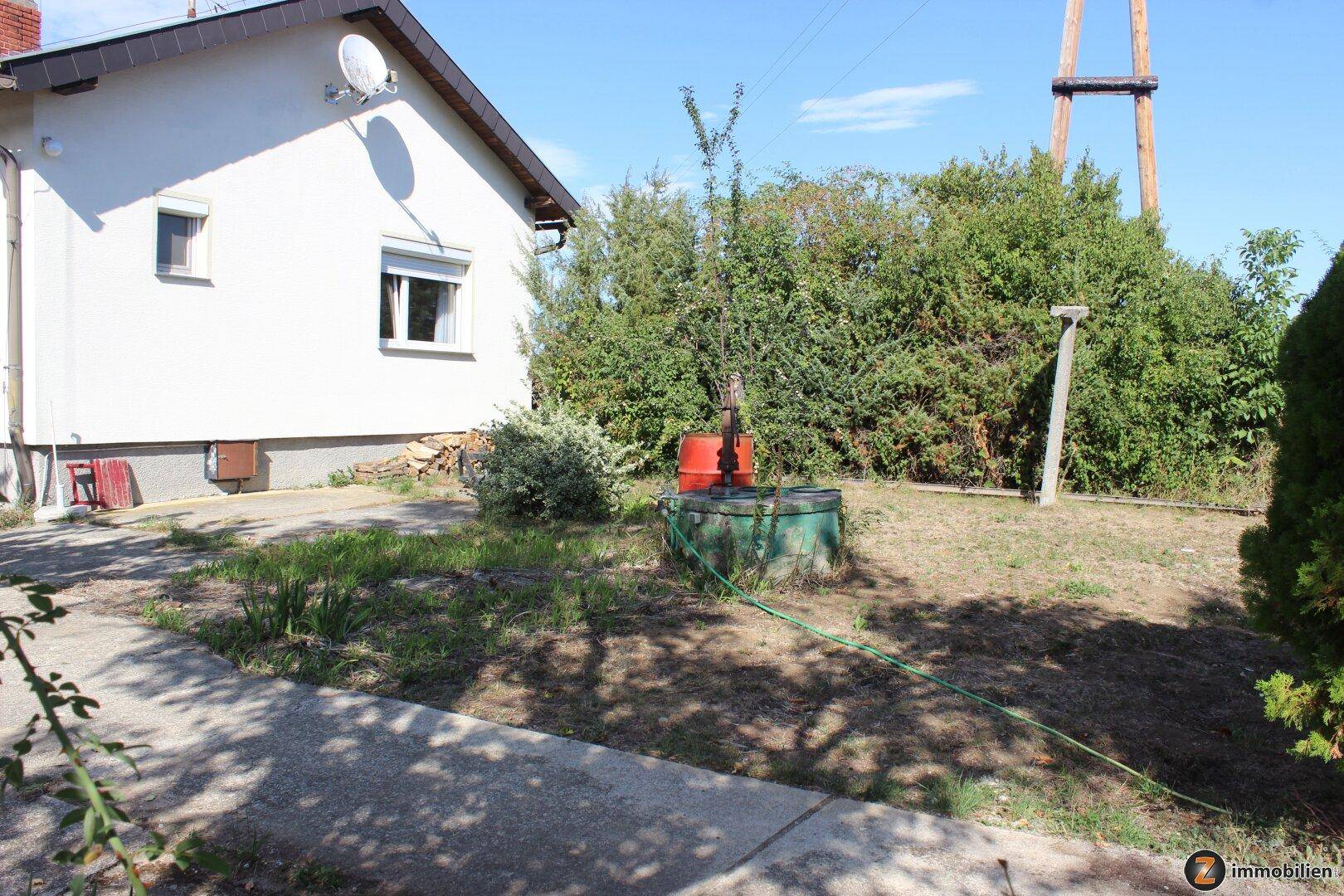 Außenbereich des Hauses mit Brunnen und üppiger Vegetation.