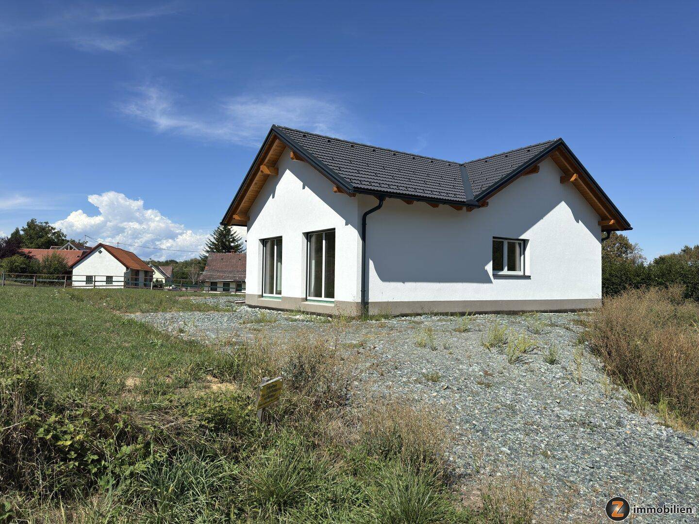 Modernes Einfamilienhaus im Neubaugebiet mit weißer Fassade und dunklem Ziegeldach.