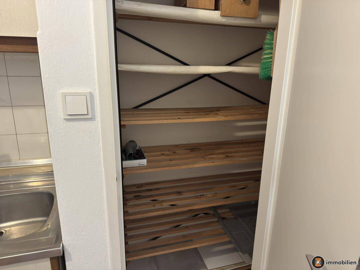 Praktischer Abstellraum mit Holzregalen für zusätzlichen Stauraum in der Wohnung.