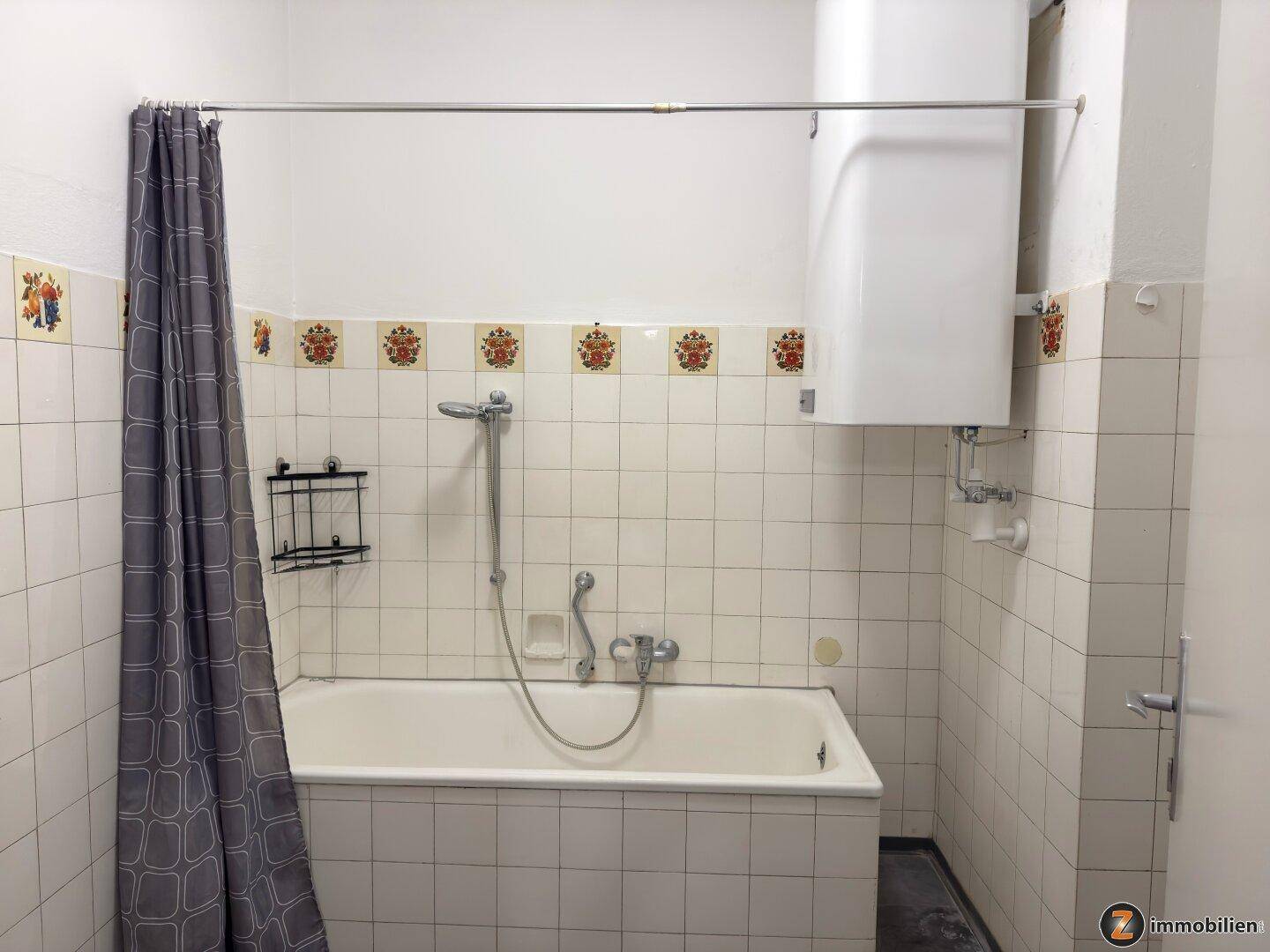 Badezimmer mit Badewanne, Duschvorhang und gefliesten Wänden in einem älteren Stil.