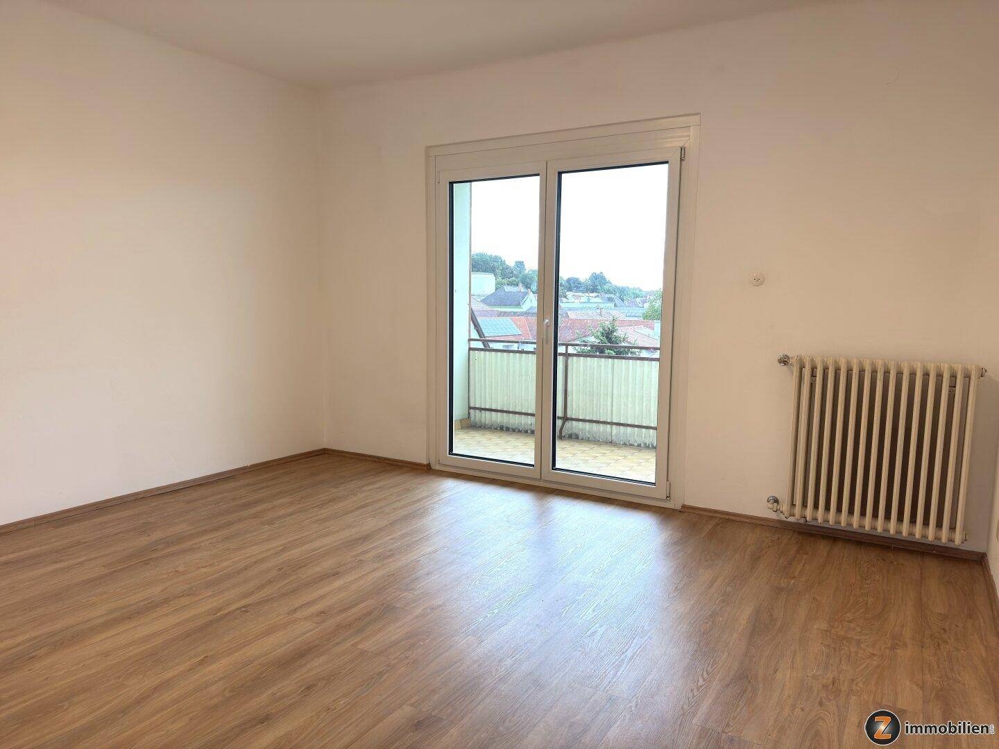Geräumiges Schlafzimmer mit Laminatboden und direktem Zugang zum privaten Balkon.