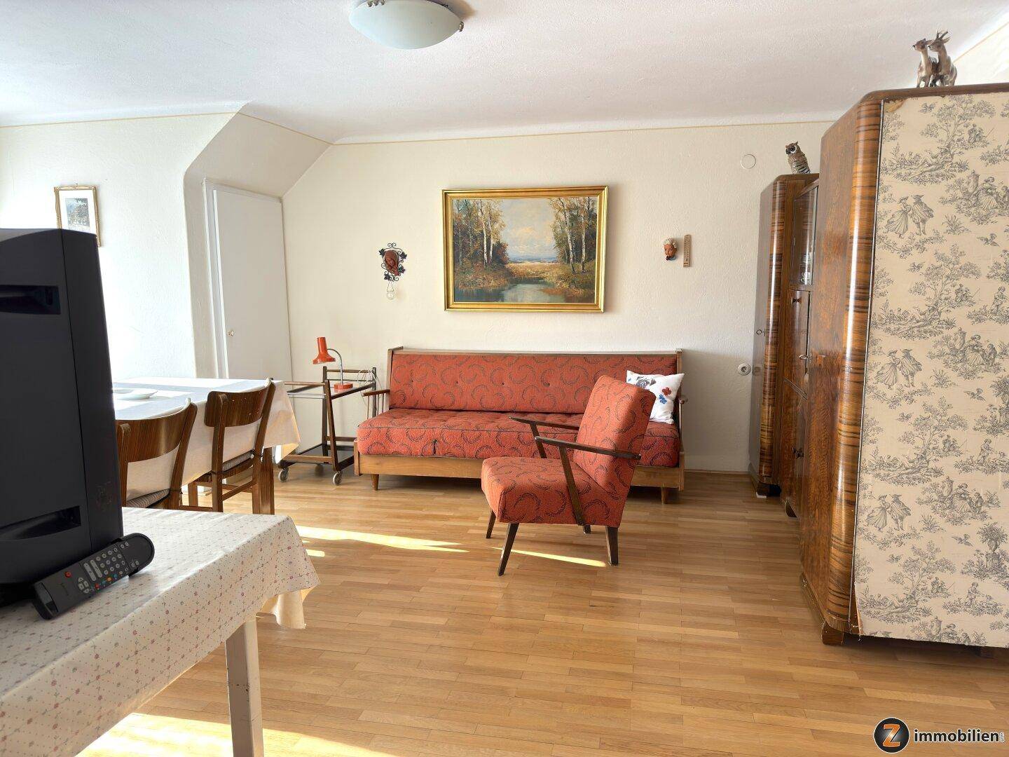 Gemütliches Wohnzimmer mit Holzboden, Sofa und Vintage-Möbeln, hell und einladend.
