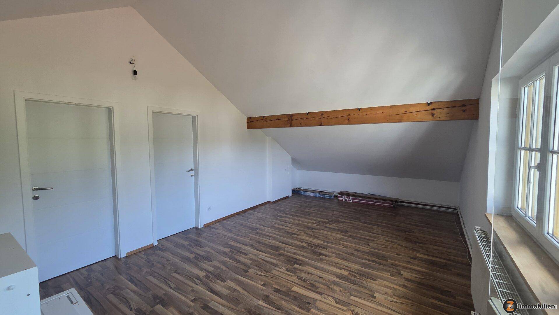 Geräumiger Dachbodenraum mit Holzbalken, Laminatboden und viel Potenzial.