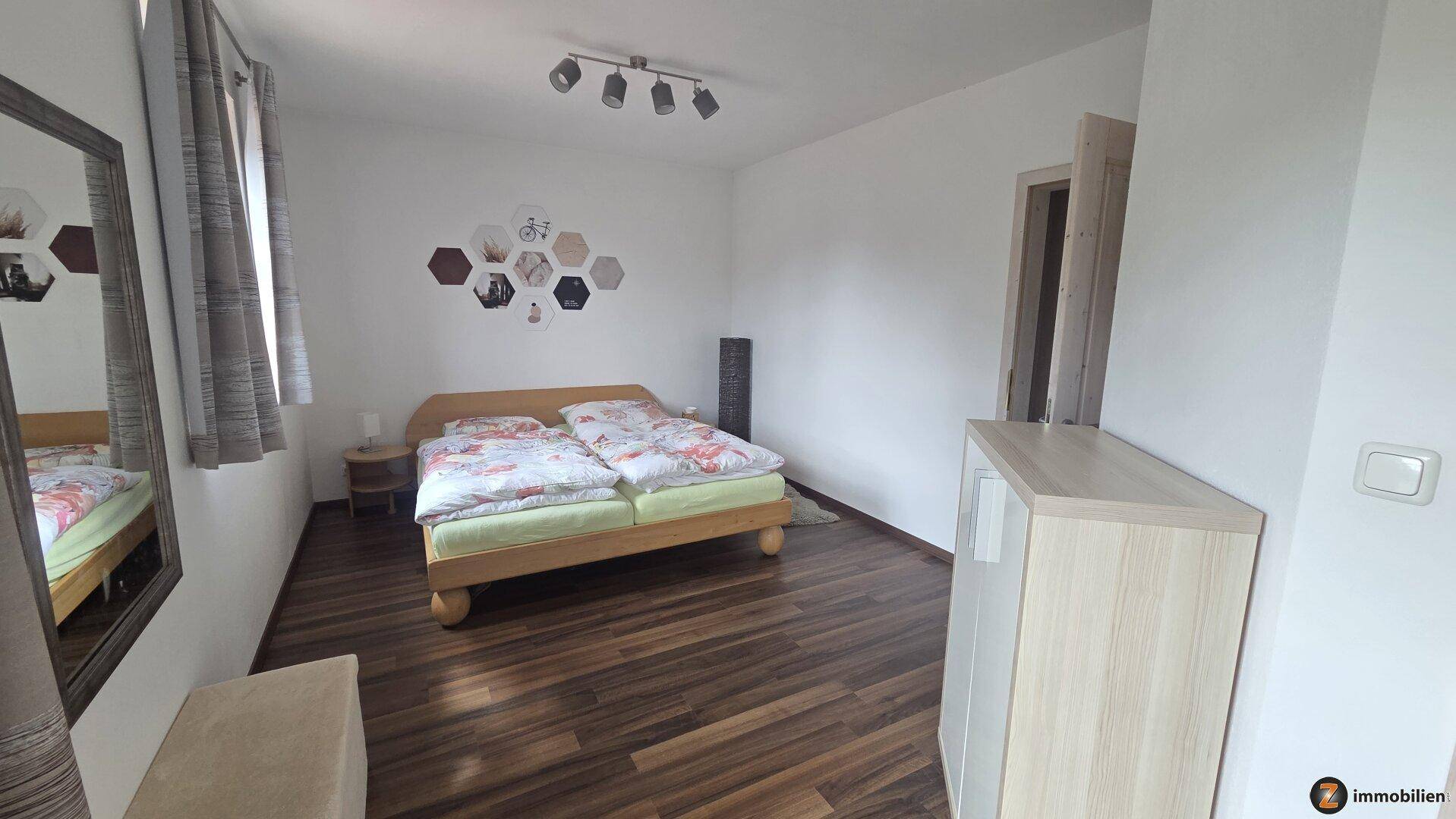 Helles Schlafzimmer mit Holzboden, Doppelbett und schlichter, moderner Dekoration.