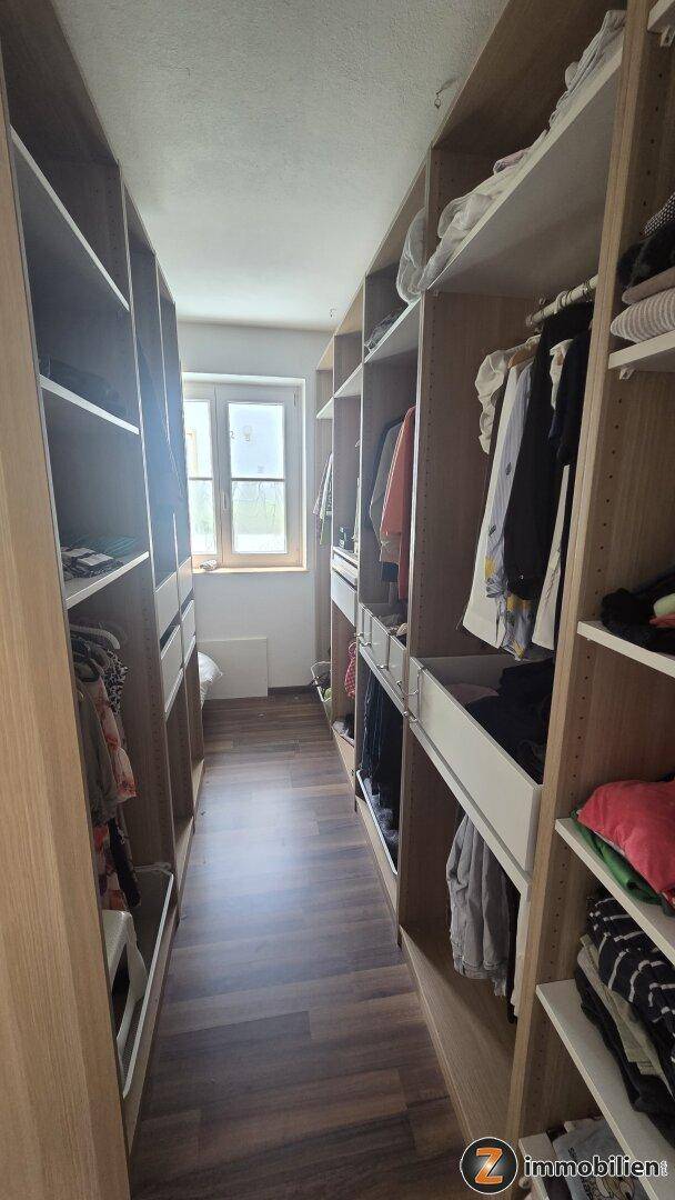 Praktischer begehbarer Kleiderschrank mit viel Stauraum und Fenster.