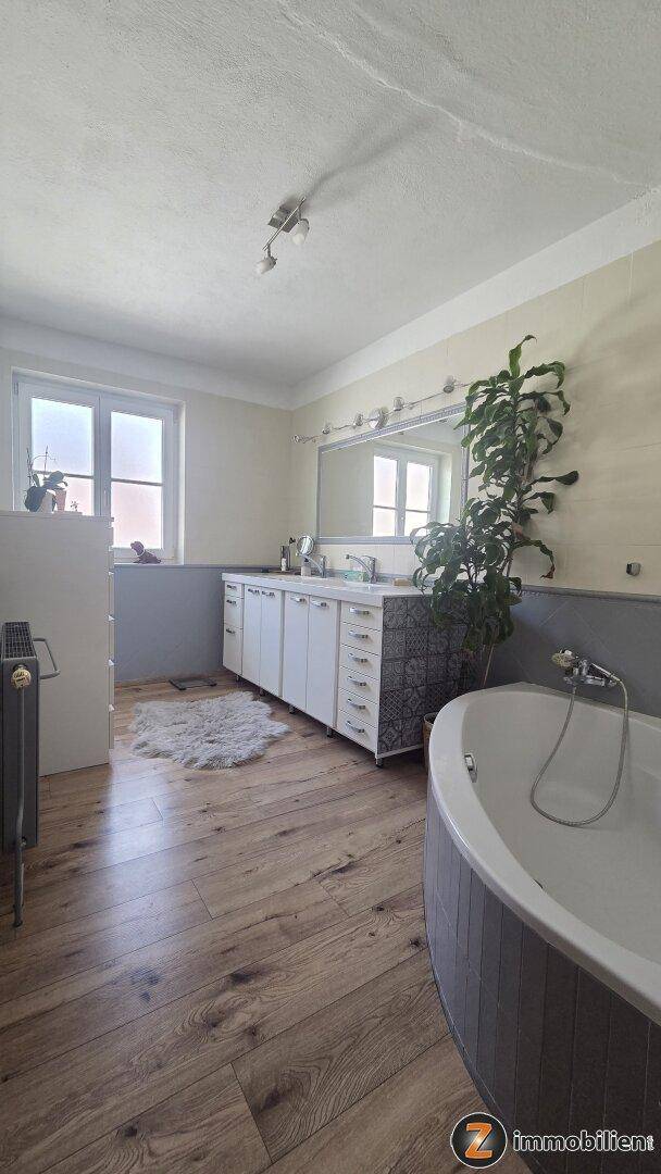 Geräumiges Badezimmer mit Badewanne, Doppelwaschbecken und Holzboden.