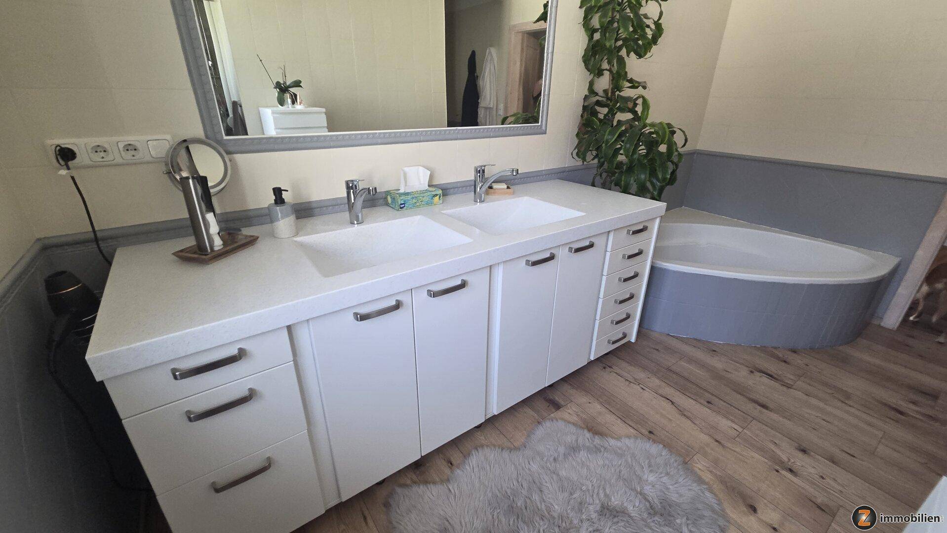 Modernes Badezimmer mit Doppelwaschbecken, großem Spiegel und Eckbadewanne.