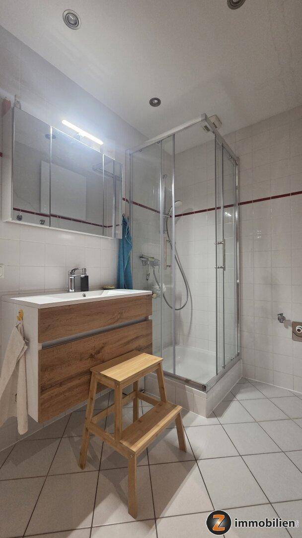 Modernes Badezimmer mit Duschkabine, Einzelwaschbecken und Fliesenboden.