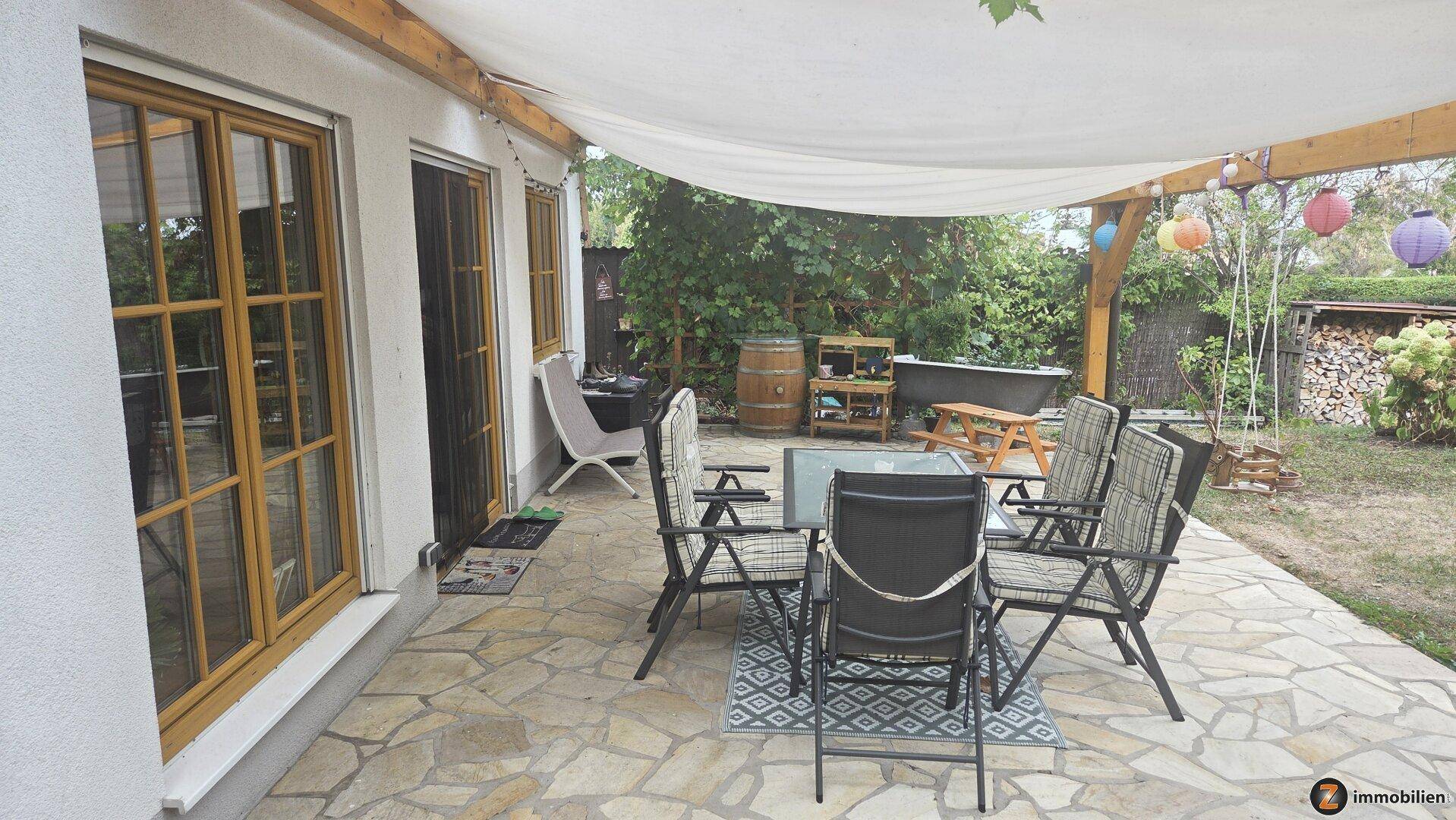 Geräumige Terrasse mit Sitzgelegenheiten, Sonnenschutz und Blick in den Garten.