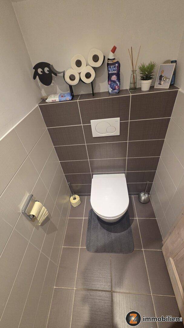 Kleines Gäste-WC mit Wand-WC und modernen Fliesen an Wänden und Boden.