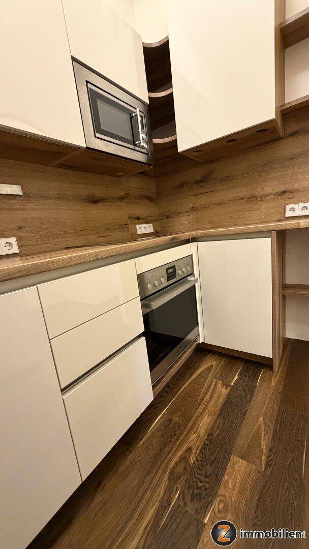 Detailansicht der modernen Küche mit Backofen, Induktionskochfeld und praktischen offenen Regalen.