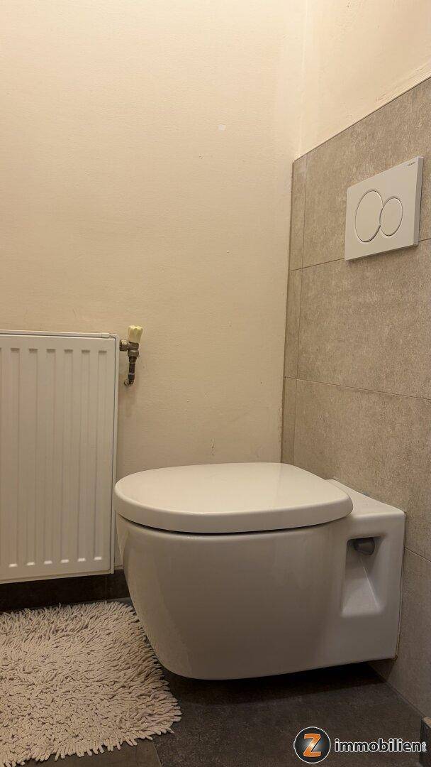 Modernes separates WC mit wandhängender Toilette und Heizkörper.