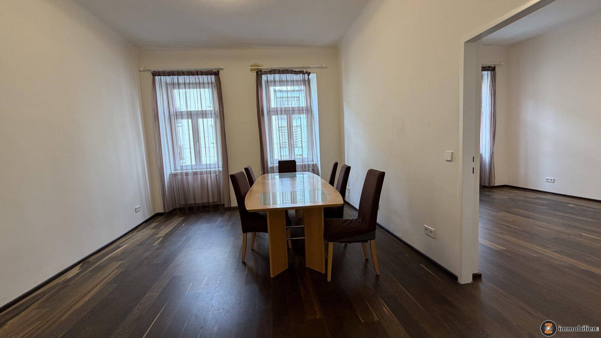 Heller Essbereich mit dunklem Holzboden und einem großen Esstisch für gesellige Runden.