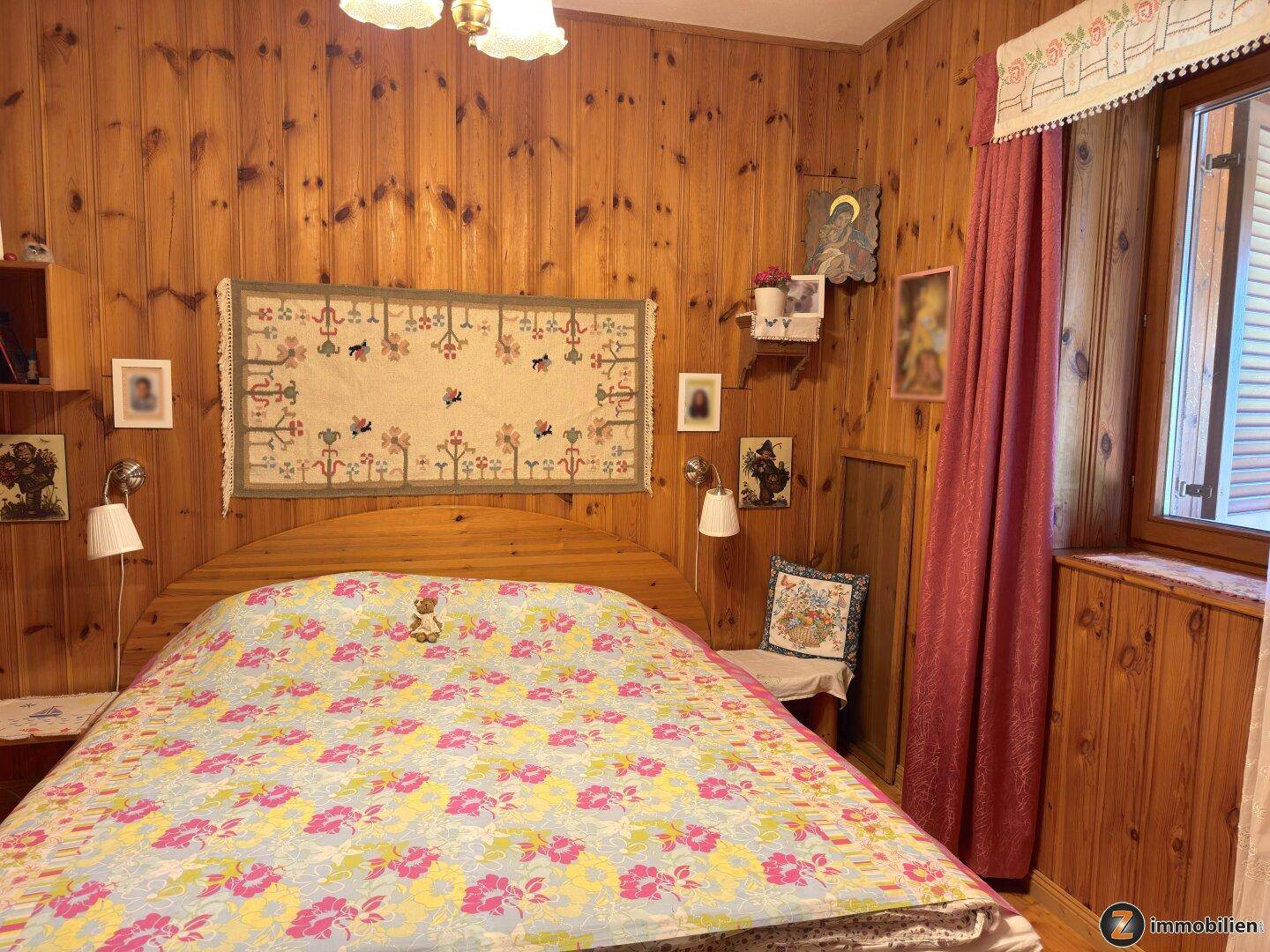 Gemütliches Schlafzimmer mit Holzwänden, Doppelbett und floraler Bettwäsche.
