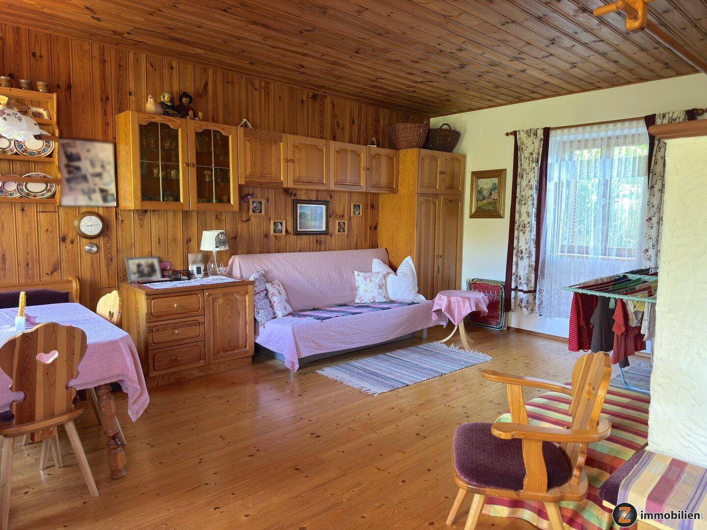 Gemütlicher Wohnbereich mit Holzwänden, Sofa und Esstisch, durchflutet von natürlichem Licht.