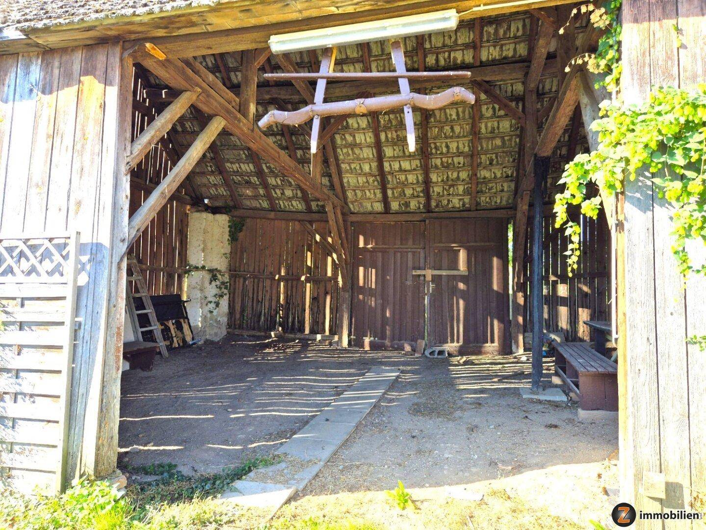 Geräumige Scheune mit Holzbalkenkonstruktion und offenem Eingang, ideal für Lagerung oder Werkstatt.