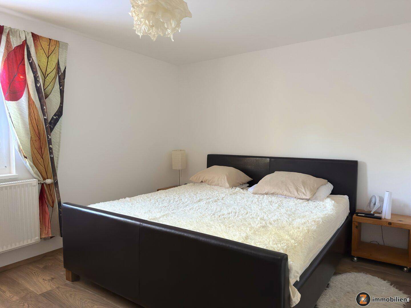 Gemütliches Schlafzimmer mit Doppelbett, Nachttisch und Laminatboden.