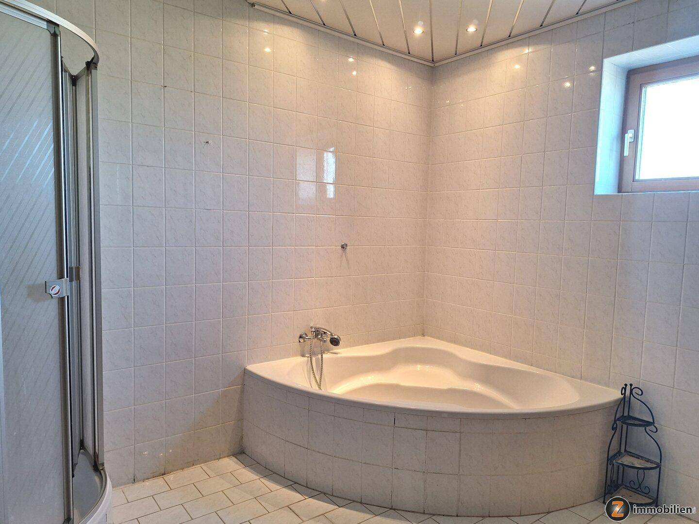 Badezimmer mit Eckbadewanne und Duschkabine, komplett gefliest.