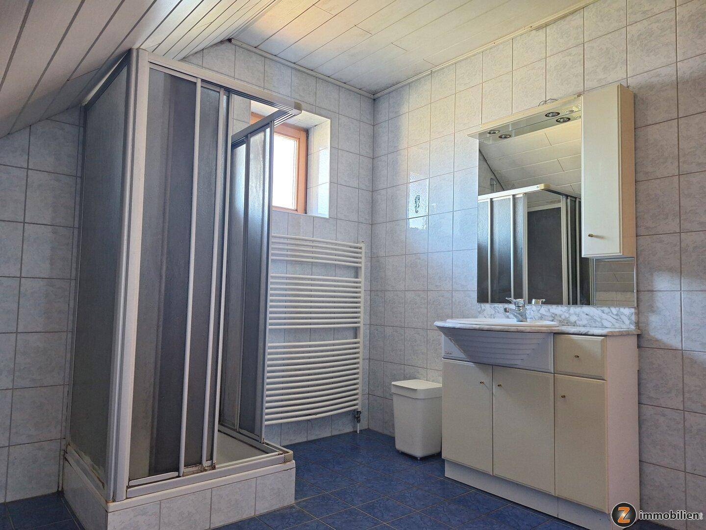 Dachgeschoss-Badezimmer mit Dusche, Waschbecken und beheiztem Handtuchhalter.