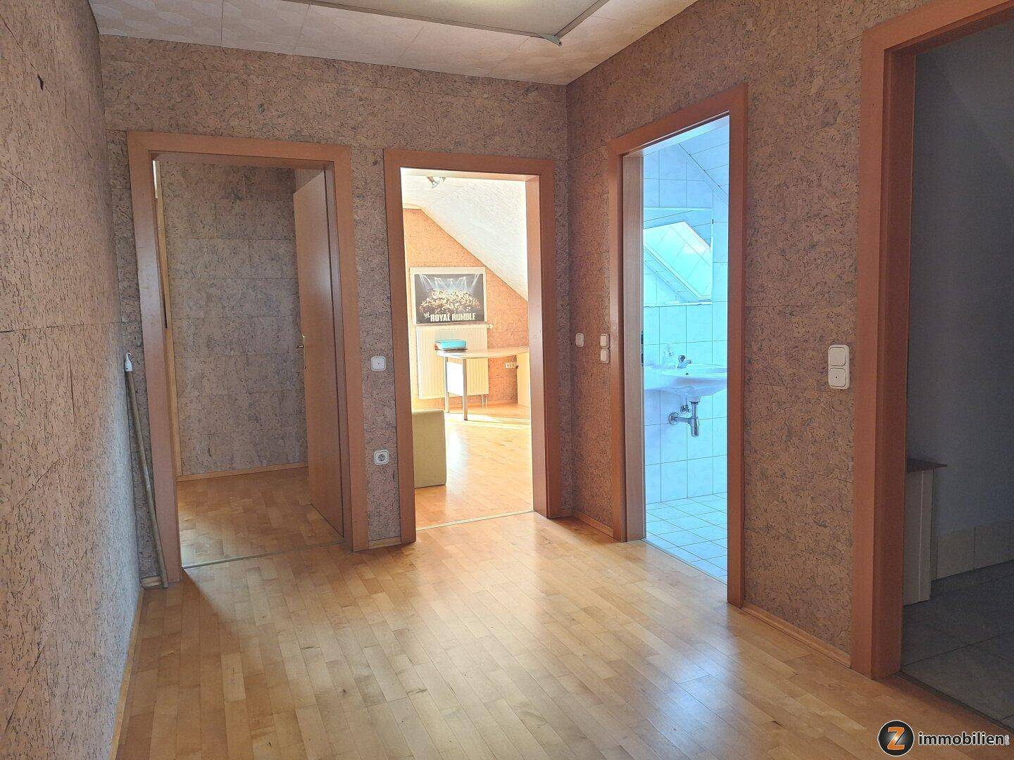 Heller Flur im Dachgeschoss mit Holzboden und Zugang zu mehreren Zimmern.