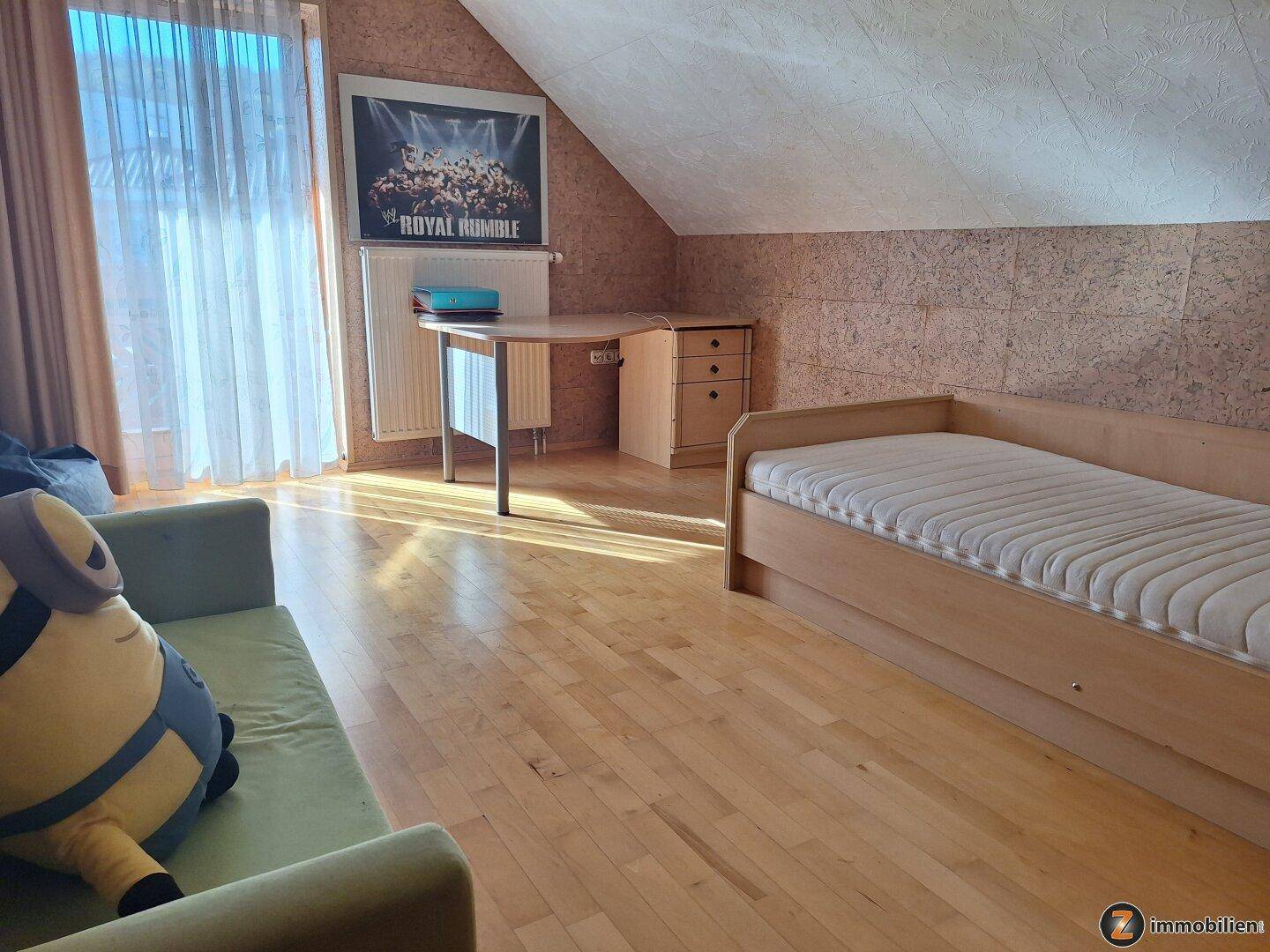 Helles Schlafzimmer im Dachgeschoss mit Einzelbett und Schreibtisch.