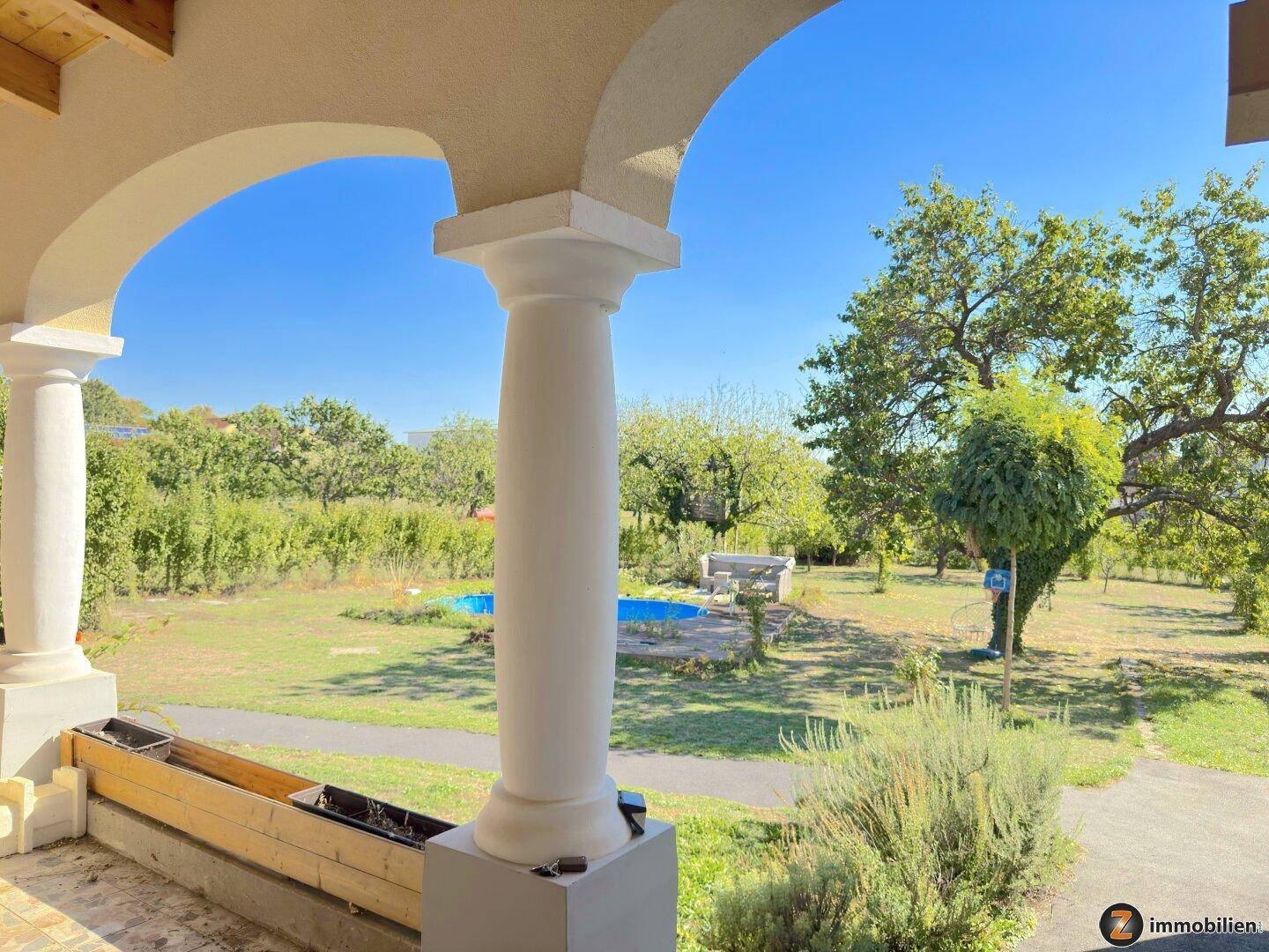 Überdachte Loggia mit Säulen bietet einen schönen Blick auf den weitläufigen Gartenbereich.