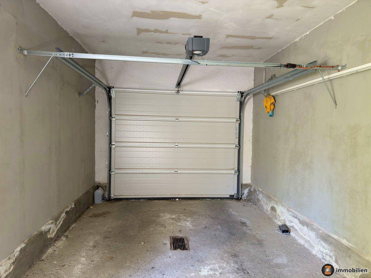 Geräumige Garage mit automatischem Tor und Betonboden.