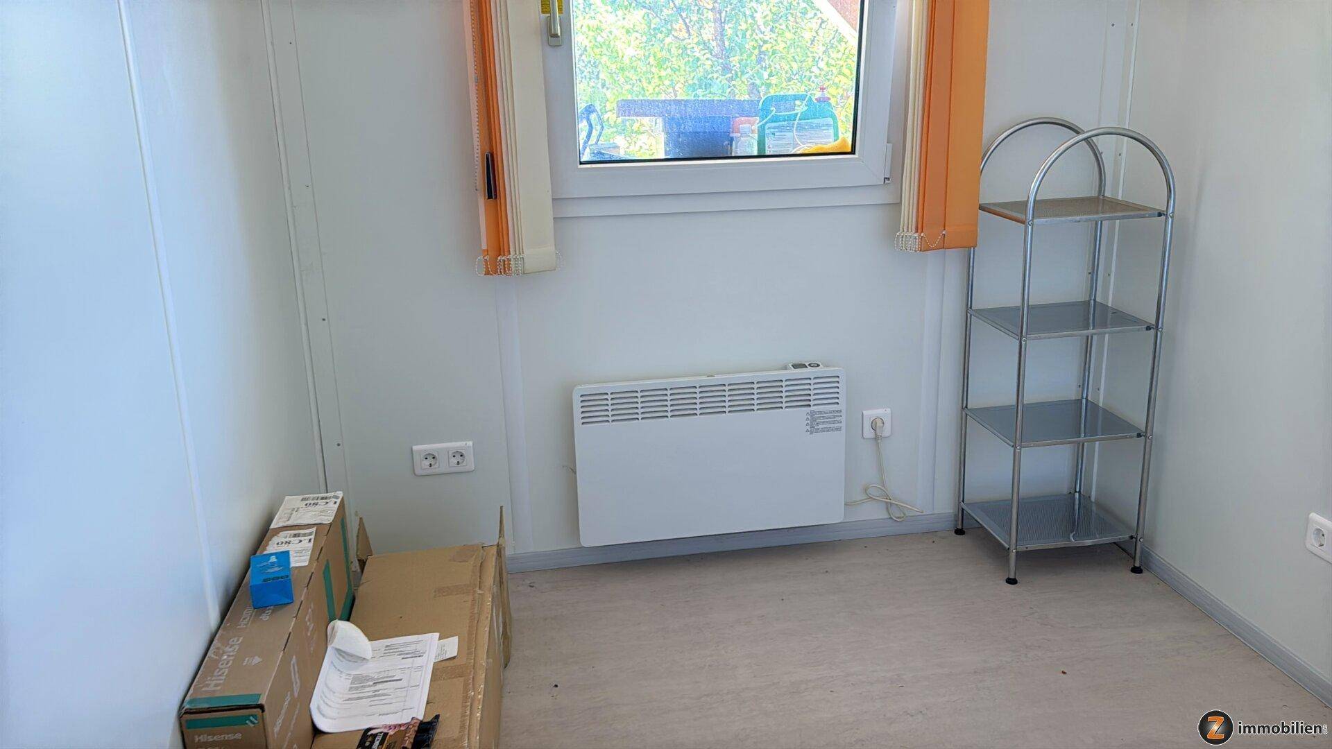 Kleiner Raum mit Fenster, Heizung und Regal, ideal als Büro oder Abstellraum.