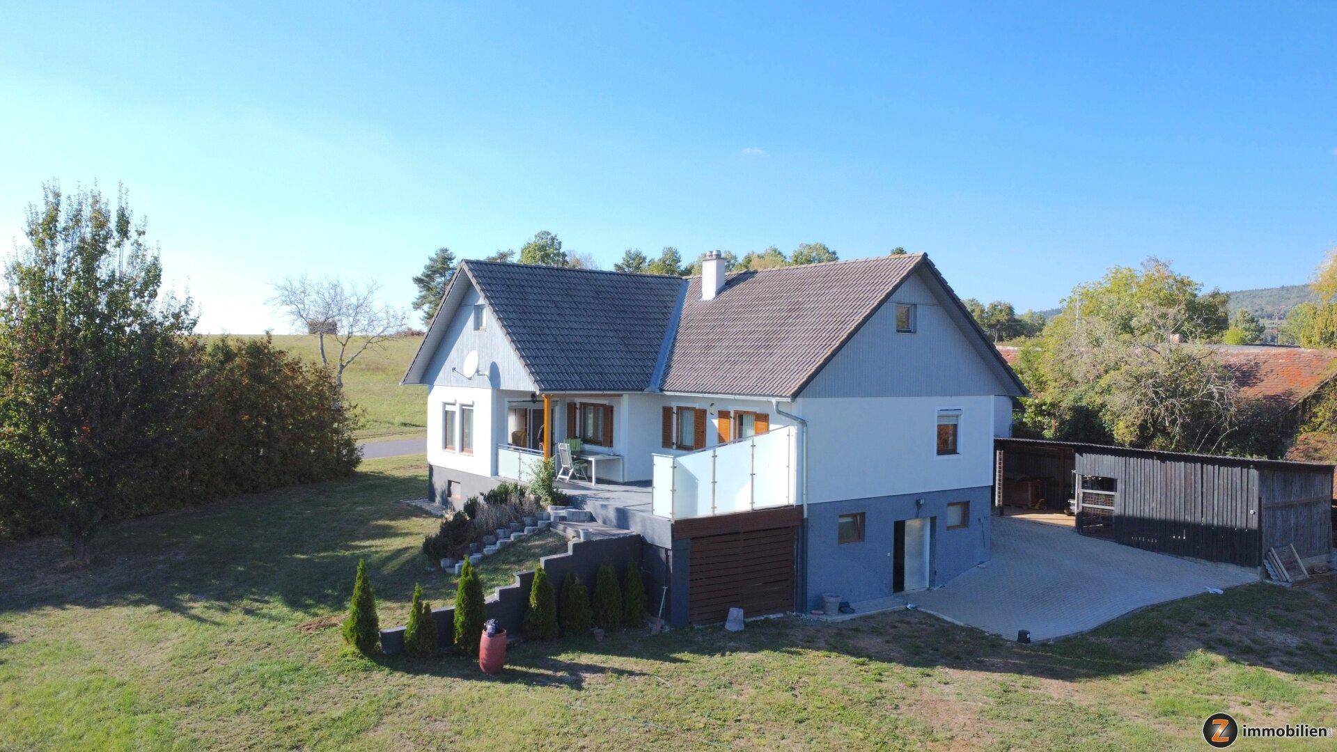 Panoramablick auf das Einfamilienhaus mit großem Grundstück und überdachtem Stellplatz.