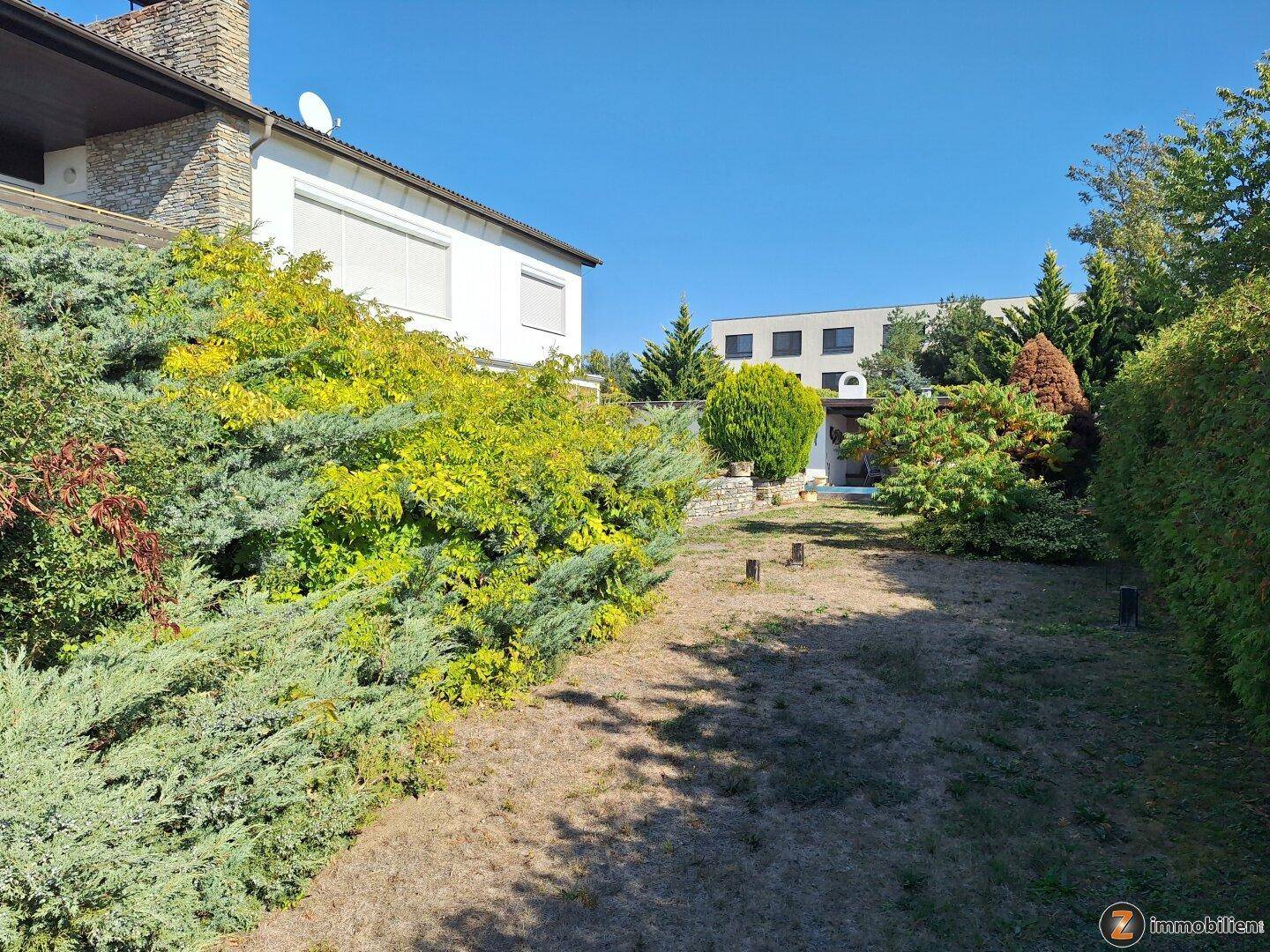 Seitenansicht des Hauses mit gepflegtem Garten und üppiger Bepflanzung.