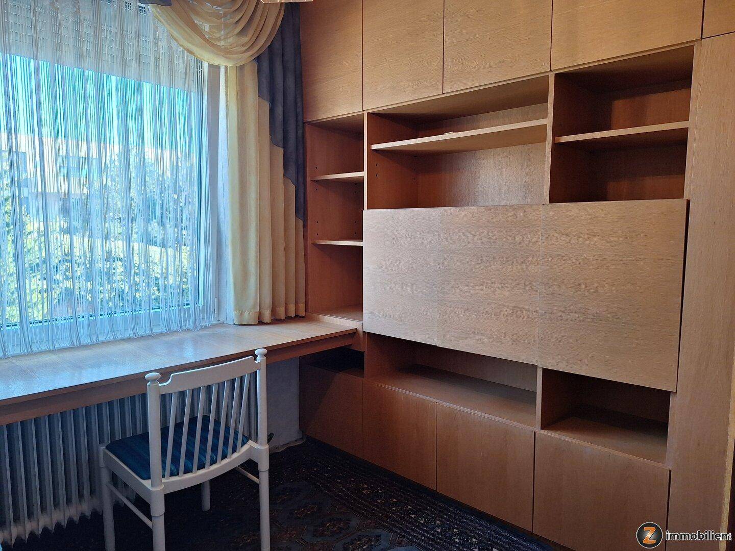 Arbeitszimmer mit großem Fenster, Einbauschränken und integriertem Schreibtisch.