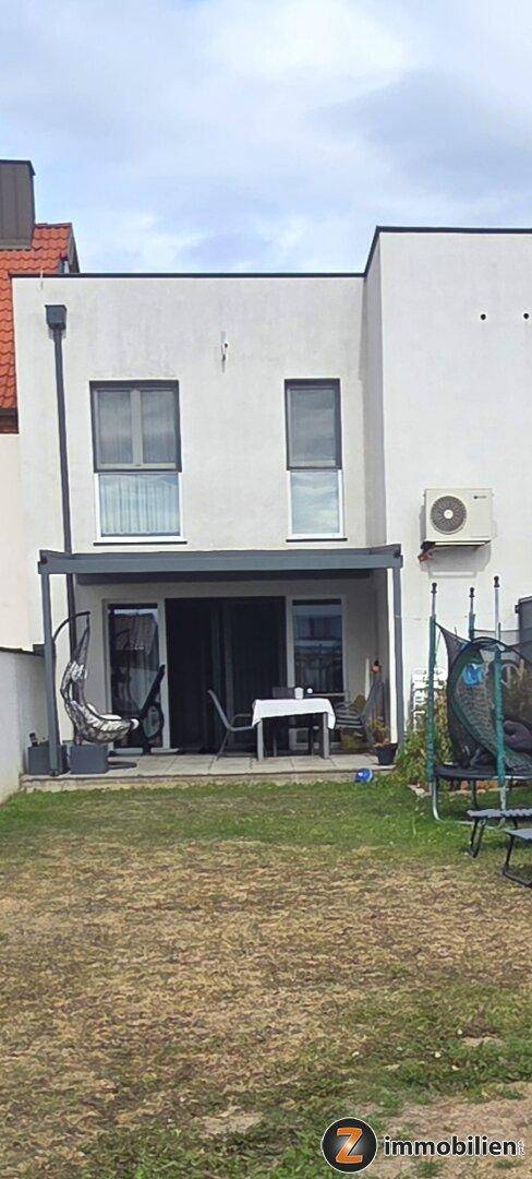 Rückansicht des Hauses mit einer möblierten Terrasse und einer Klimaanlage an der Fassade.