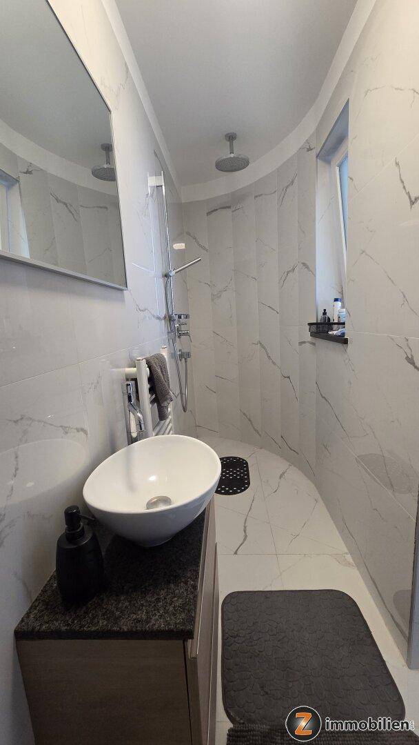 Modernes Badezimmer mit stilvollem Waschbecken, Spiegel und begehbarer Dusche.