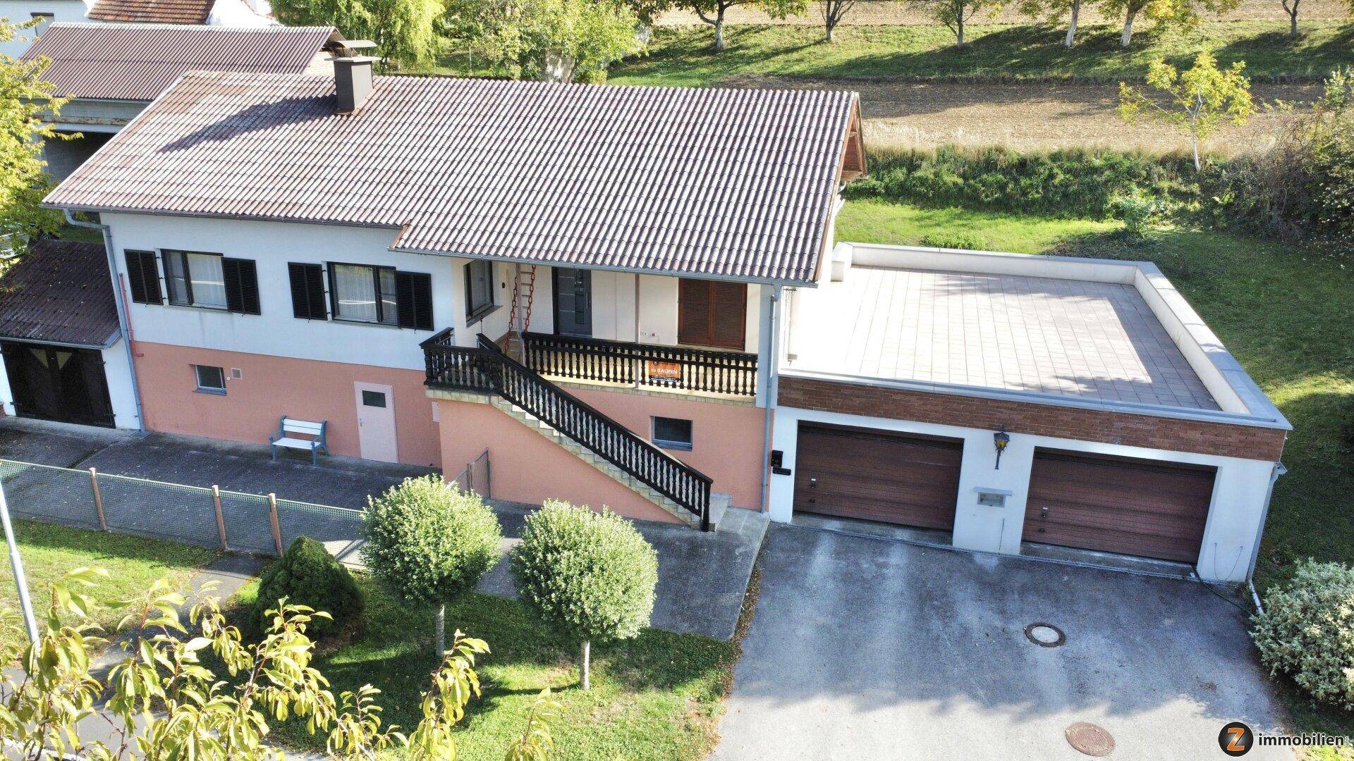 Ansicht des Hauses von oben mit Dachterrasse, Doppelgarage und gepflegtem Vorgarten.