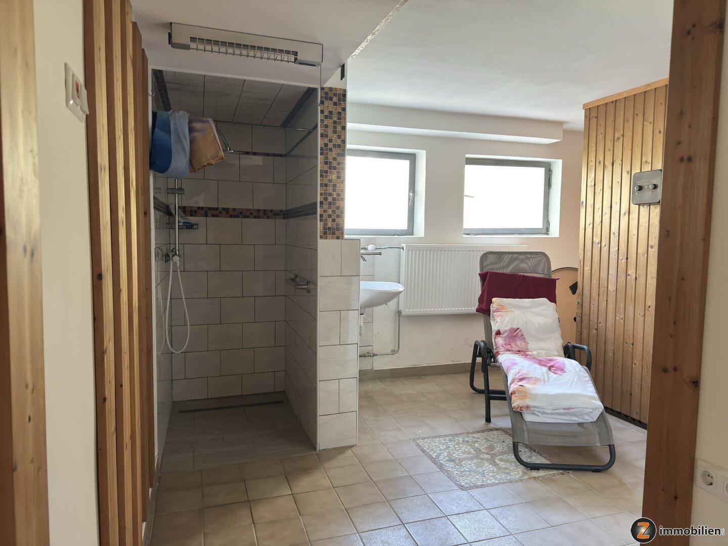 Wellnessbereich mit Dusche, Waschbecken und Liegefläche für Entspannung.