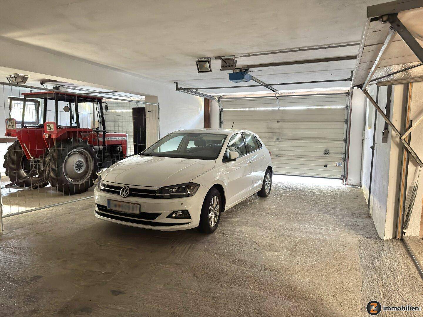 Große Garage mit einem Auto und einem Traktor, ideal für Hobby und Arbeit.