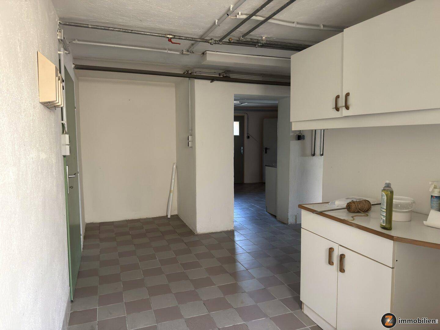 Hauswirtschaftsraum im Keller mit Stauraum und gefliestem Boden.