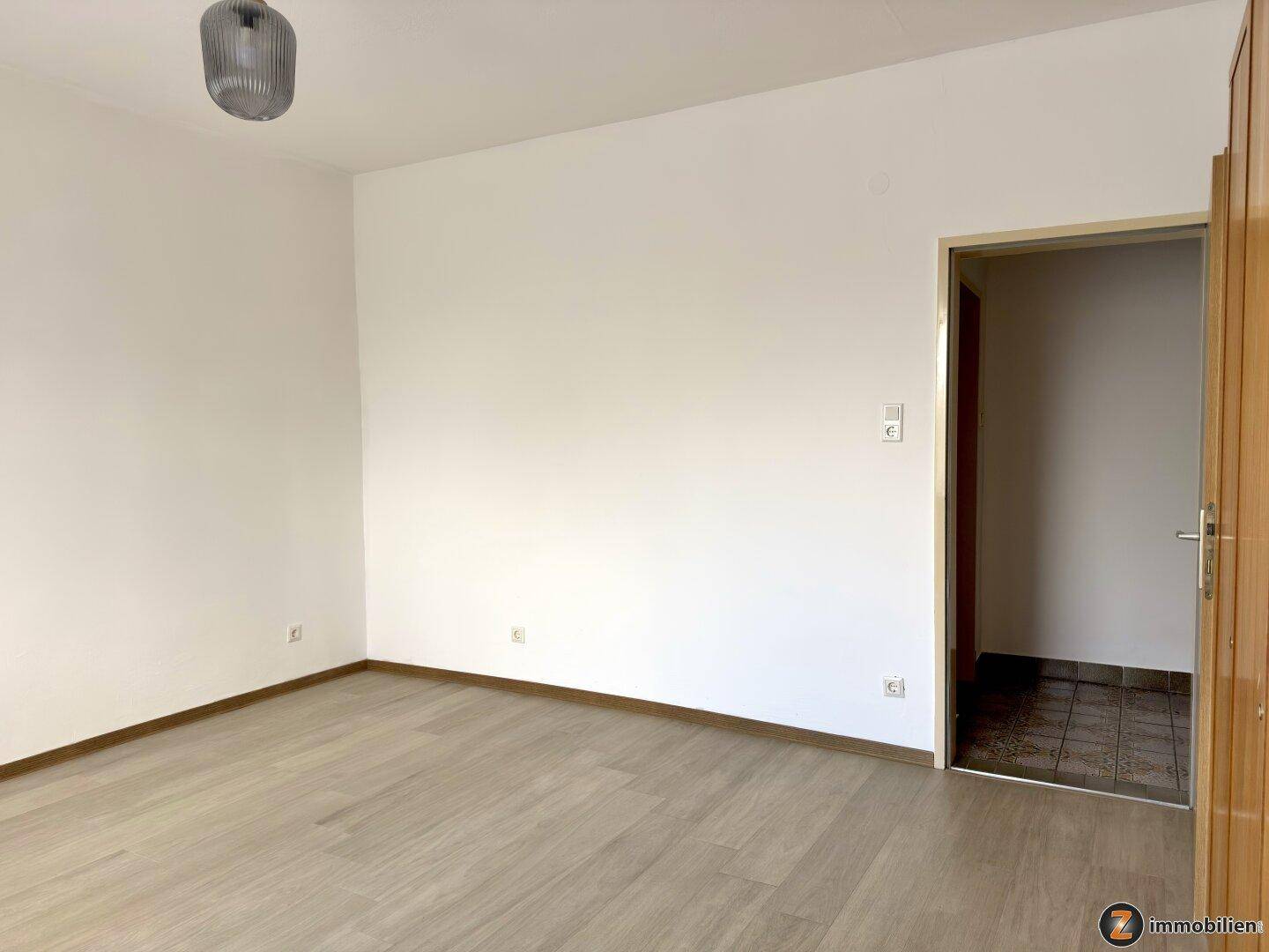 Schlafzimmer mit Laminatboden und Zugang zu einem weiteren Raum.