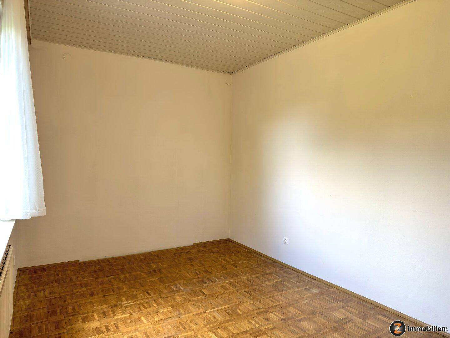 Gemütliches Schlafzimmer mit Parkettboden und einfacher Deckenverkleidung.