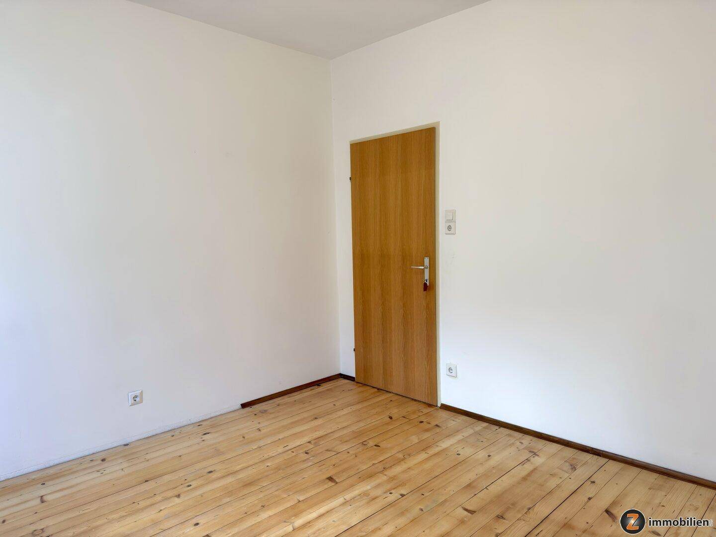 Helles Schlafzimmer mit Holzboden und weiß gestrichenen Wänden.