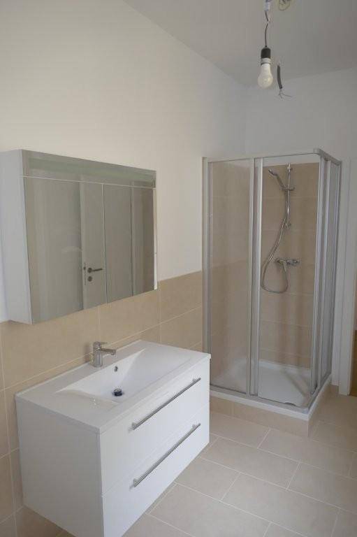 Helles Badezimmer mit Duschkabine, Waschbeckenunterschrank und Spiegelschrank.