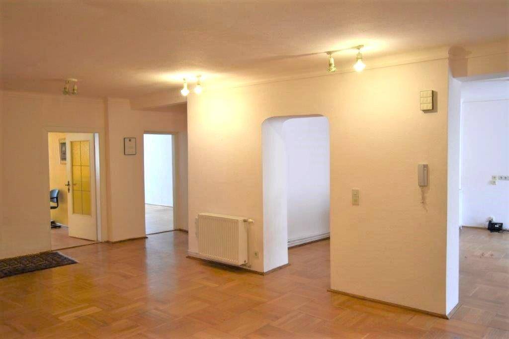 Geräumiger Flur oder offener Wohnbereich mit Parkettboden, Heizkörper und einem Durchgangsbogen.