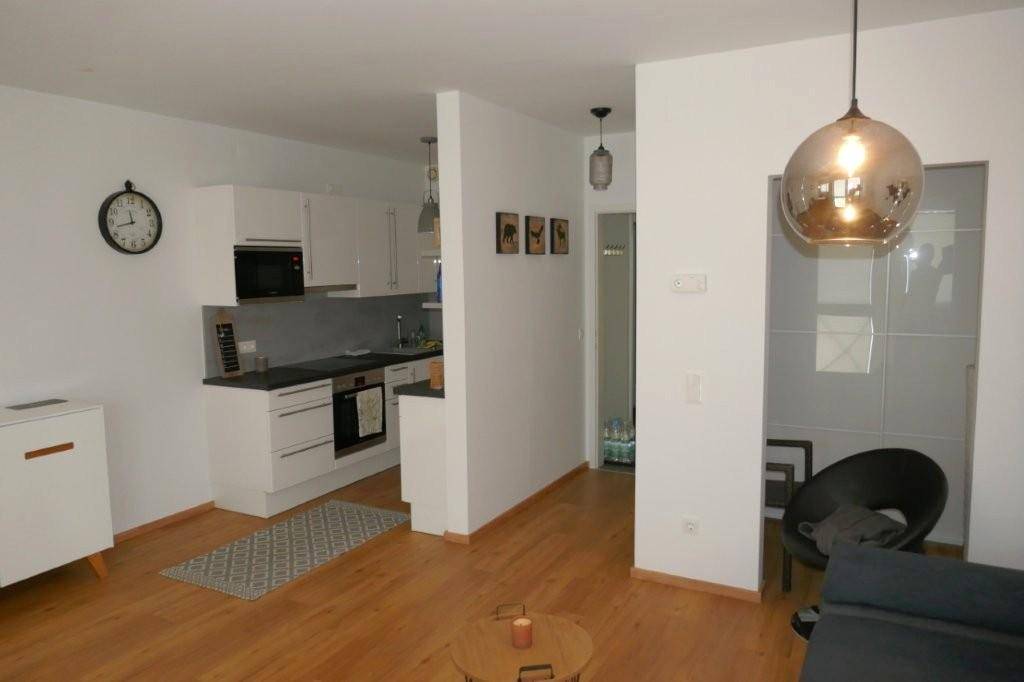 Moderne Einbauküche mit weißen Hochglanzfronten und integrierten Geräten in offenem Wohnbereich.