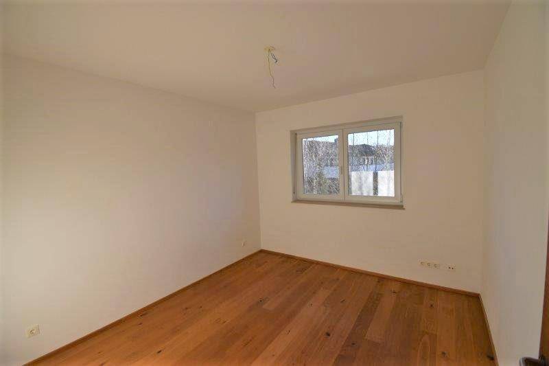 Helles Schlafzimmer mit warmem Holzboden und einem großen Fenster für viel Tageslicht.
