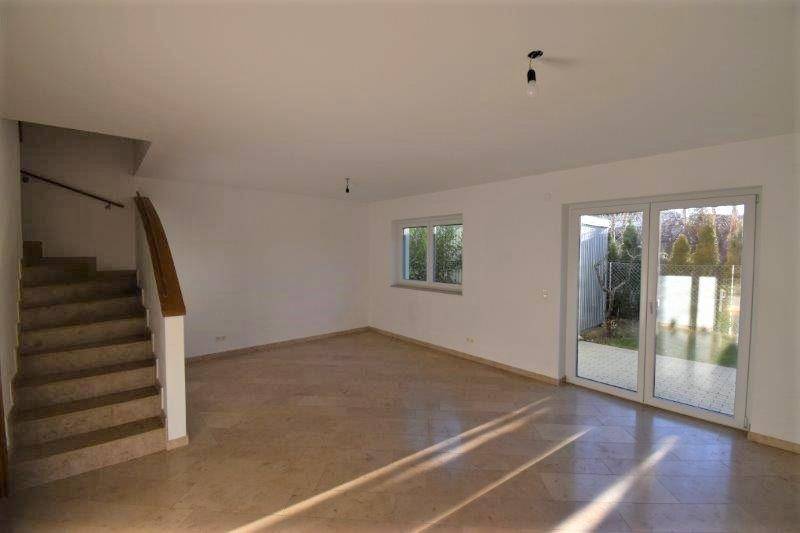 Geräumiges Wohnzimmer mit Treppe und direktem Zugang zum Gartenbereich durch eine Terrassentür.