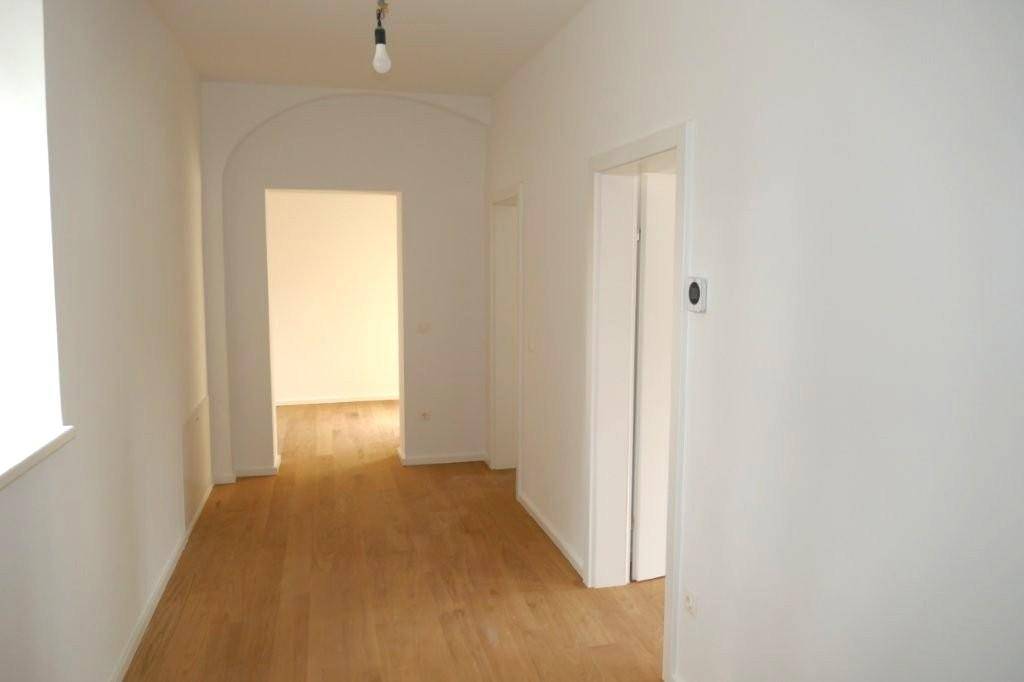 Heller Flur mit Holzfußboden und einem eleganten Bogendurchgang zu weiteren Räumen.