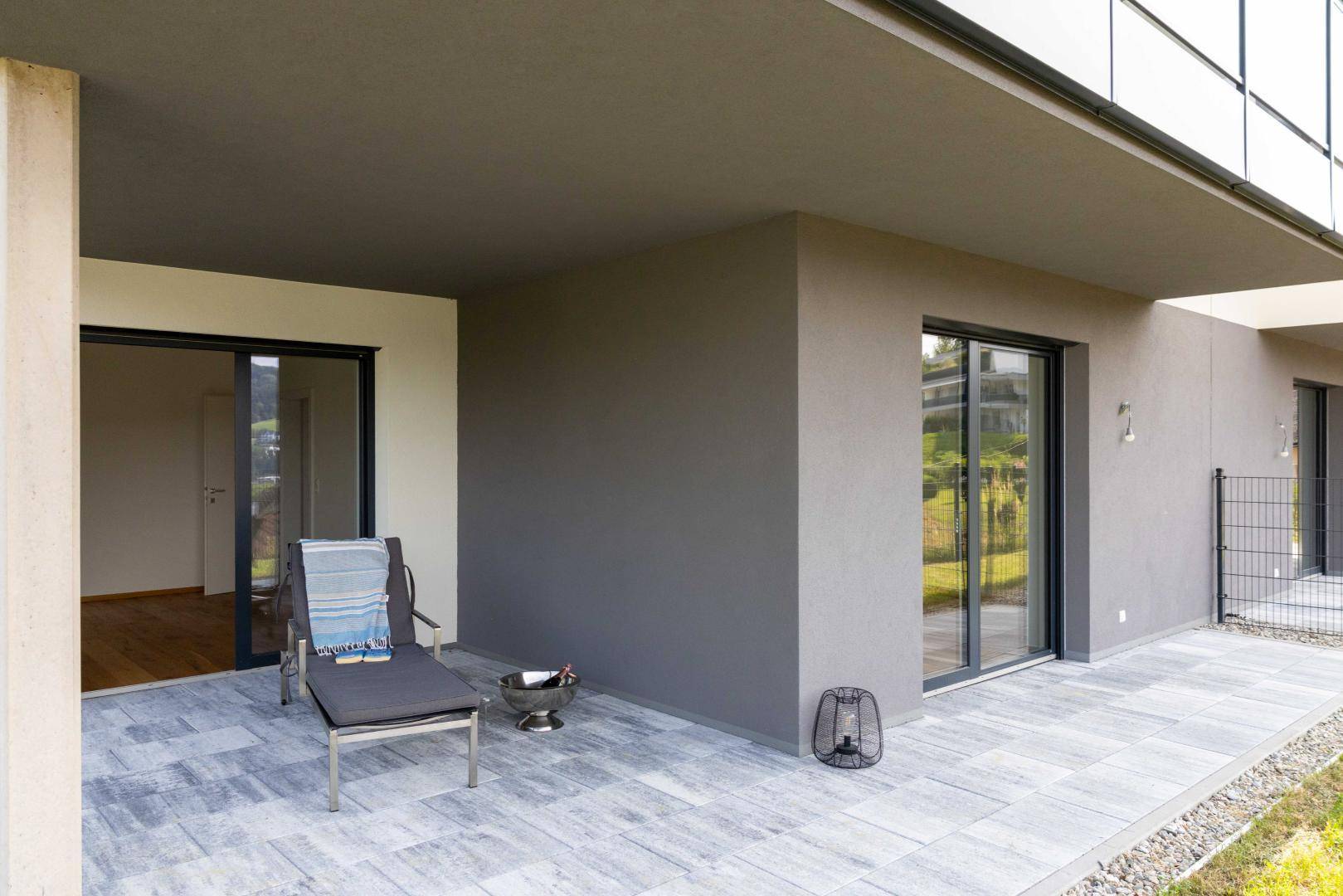 Großzügige Terrasse mit Fliesenboden und Liegestuhl, ideal für Entspannung im Freien.