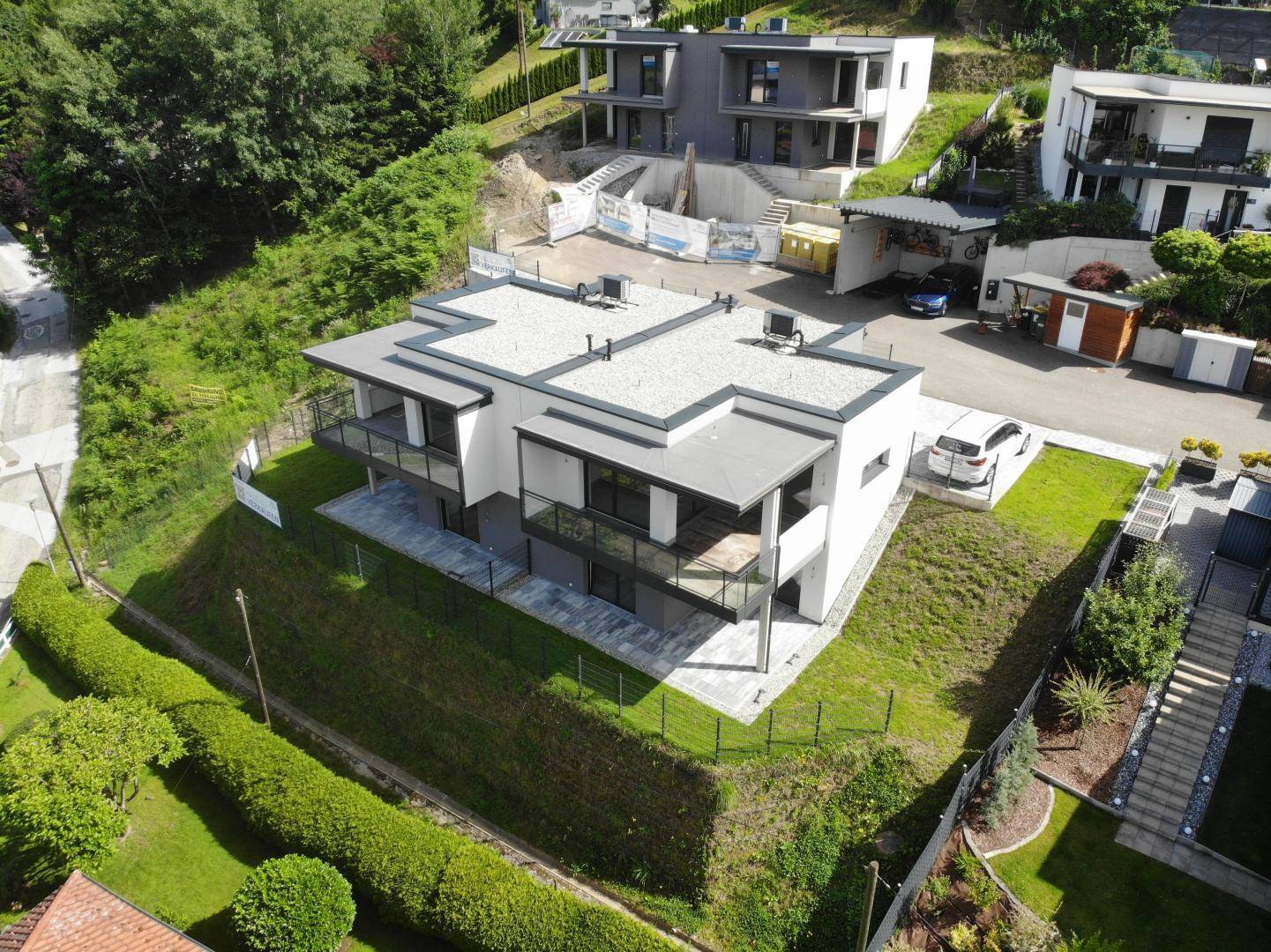 Luftaufnahme einer modernen Wohnanlage mit mehreren Gebäuden und grüner Umgebung.
